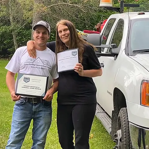 Two of the Stokes Roofing team with award certificates beside a work truck