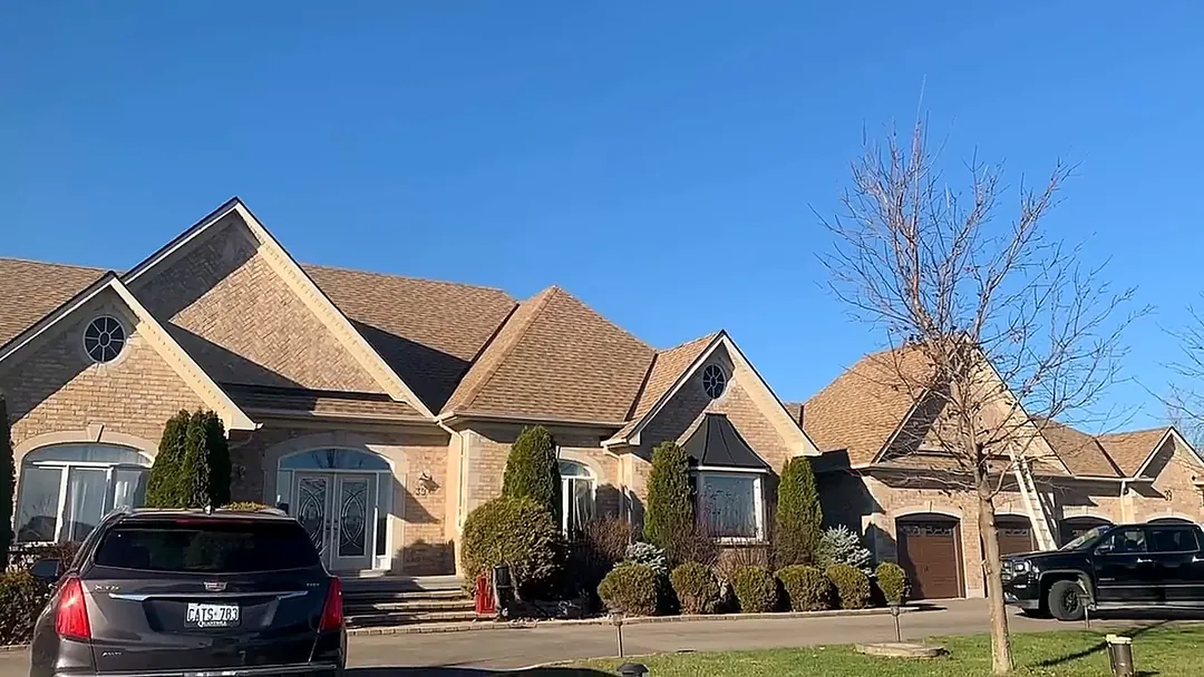 Brick home with several steep gables and a light brown shingle roof